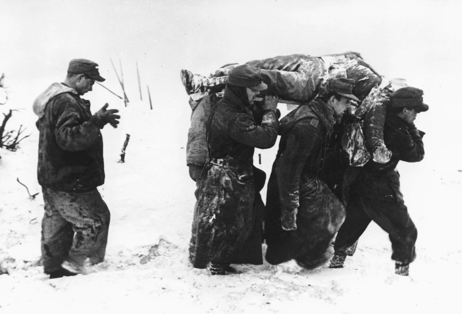 German prisoners of war carry the body of an American soldier through deep snow during the Battle of the Bulge, in the Ardennes sector of Belgium in late 1944. Nearby, German and U.S. soldiers shared a Christmas Eve dinner. (AP)